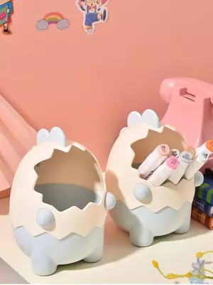 Органайзер в виде мультяшного динозавра в яичной скорлупе.